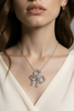 On model view of Edwardian diamond bow pendant in platinum with pavé old mine–cut diamonds on cable chain.