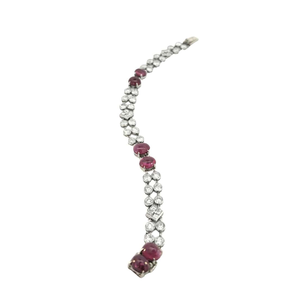 Elegant platinum bracelet with ruby cabochons and sparkling diamond rows shown in angled full-length view.