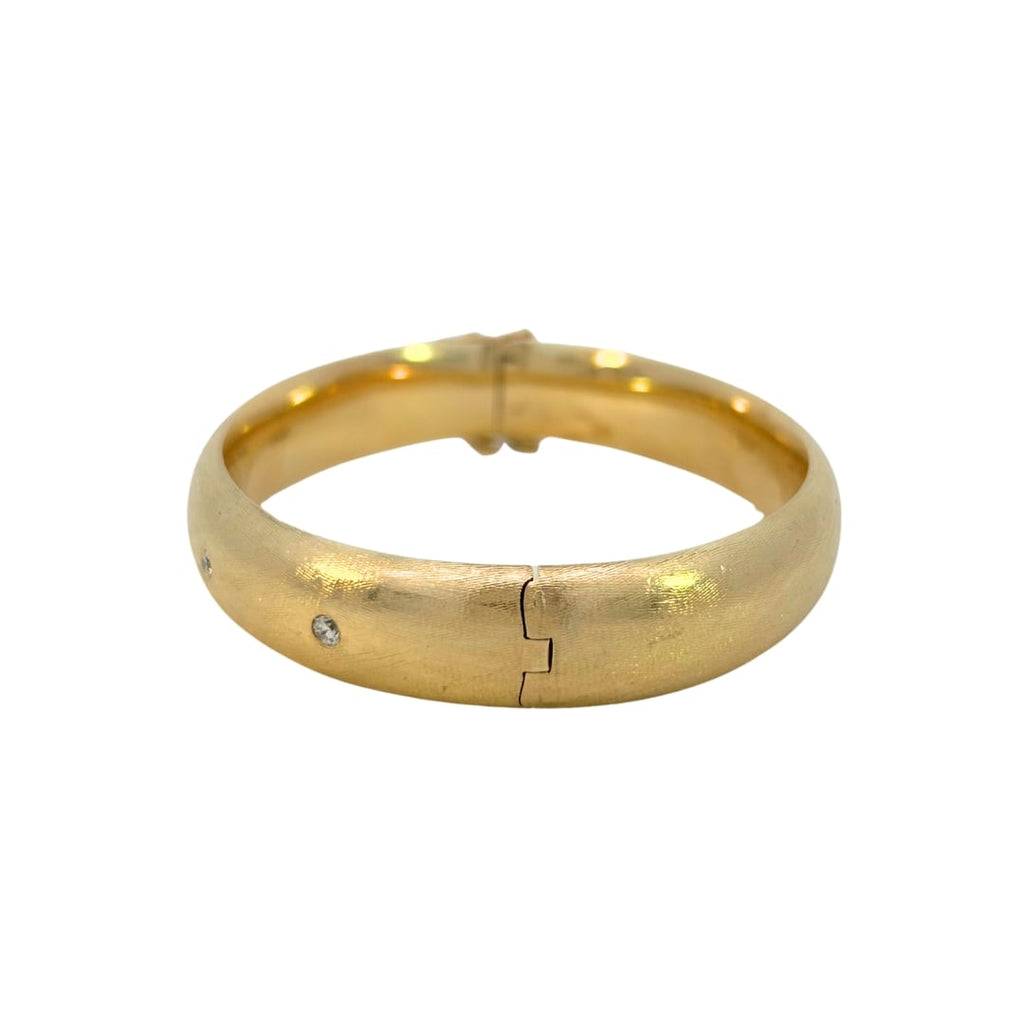 Side view of hinged gold bangle with clasp and safety chain