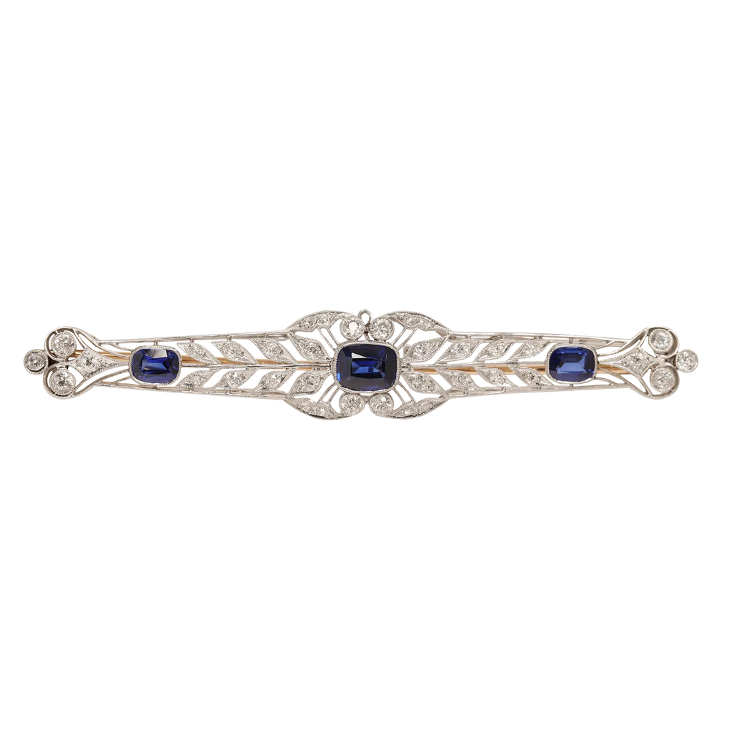Antique Edwardian platinum wreath bar pin with 36 European-cut diamonds totaling approximately 1.29 carats and three cushion-cut synthetic sapphires.