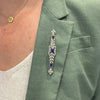 Antique Edwardian platinum wreath bar pin with 36 European-cut diamonds totaling approximately 1.29 carats and three cushion-cut synthetic sapphires.