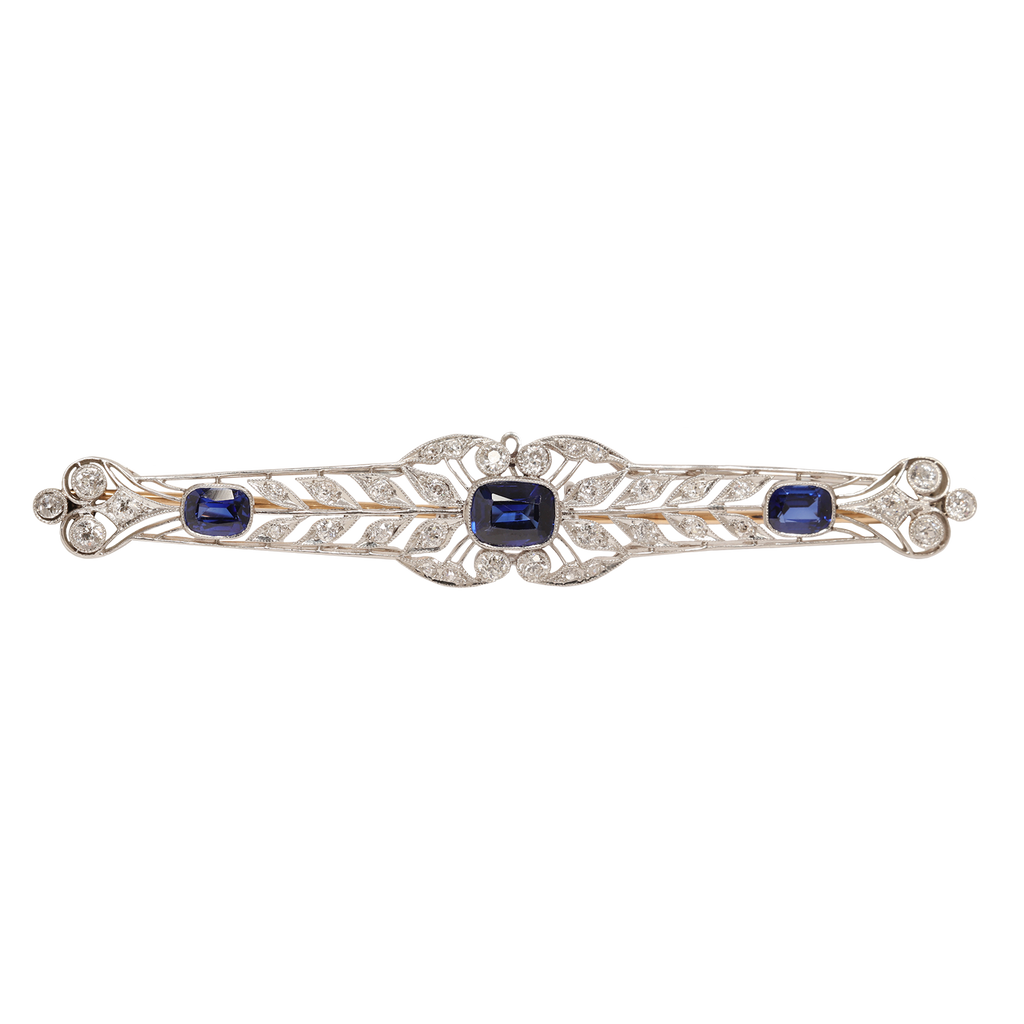 Edwardian sapphire and diamond bar pin in platinum with a delicate repeating wreath motif and diamonds set on the openwork. The pin stem is yellow gold.
