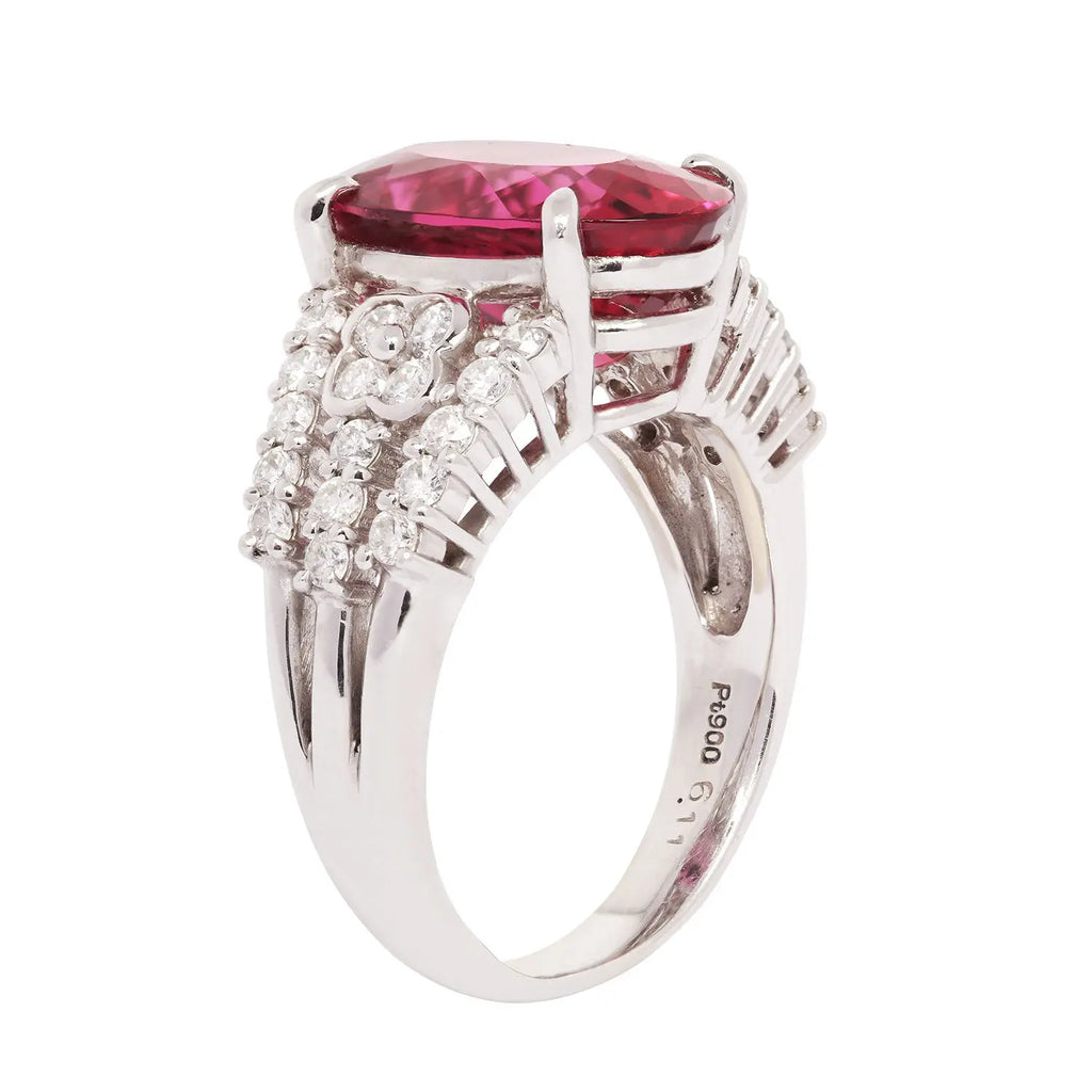 Side view of a platinum ring featuring a 6.11 carat oval rubellite tourmaline accented by rows of round brilliant diamonds.