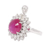 Side view of a platinum ring showcasing a cabochon pink sapphire surrounded by brilliant round diamond accents.