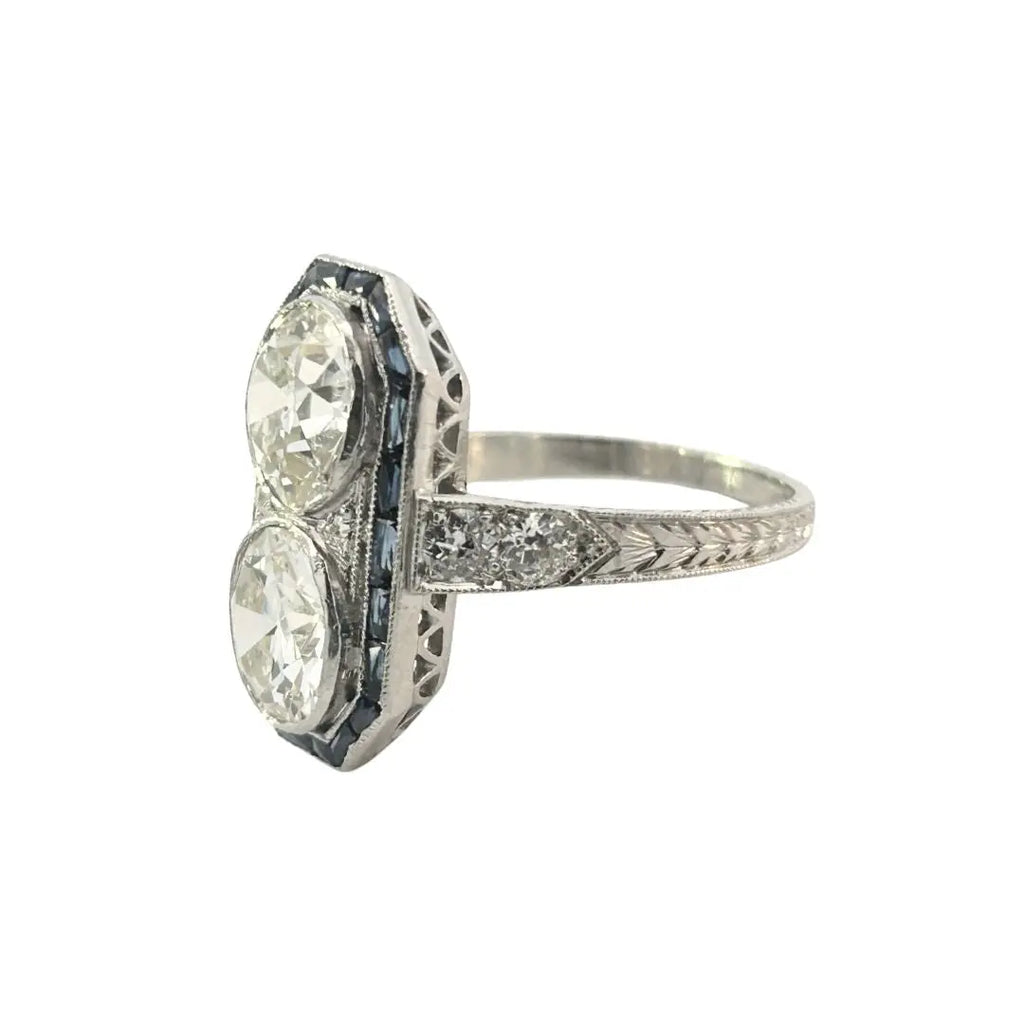 Platinum Art Deco double diamond and sapphire halo dinner ring showing engraved shoulders and milgrain detail