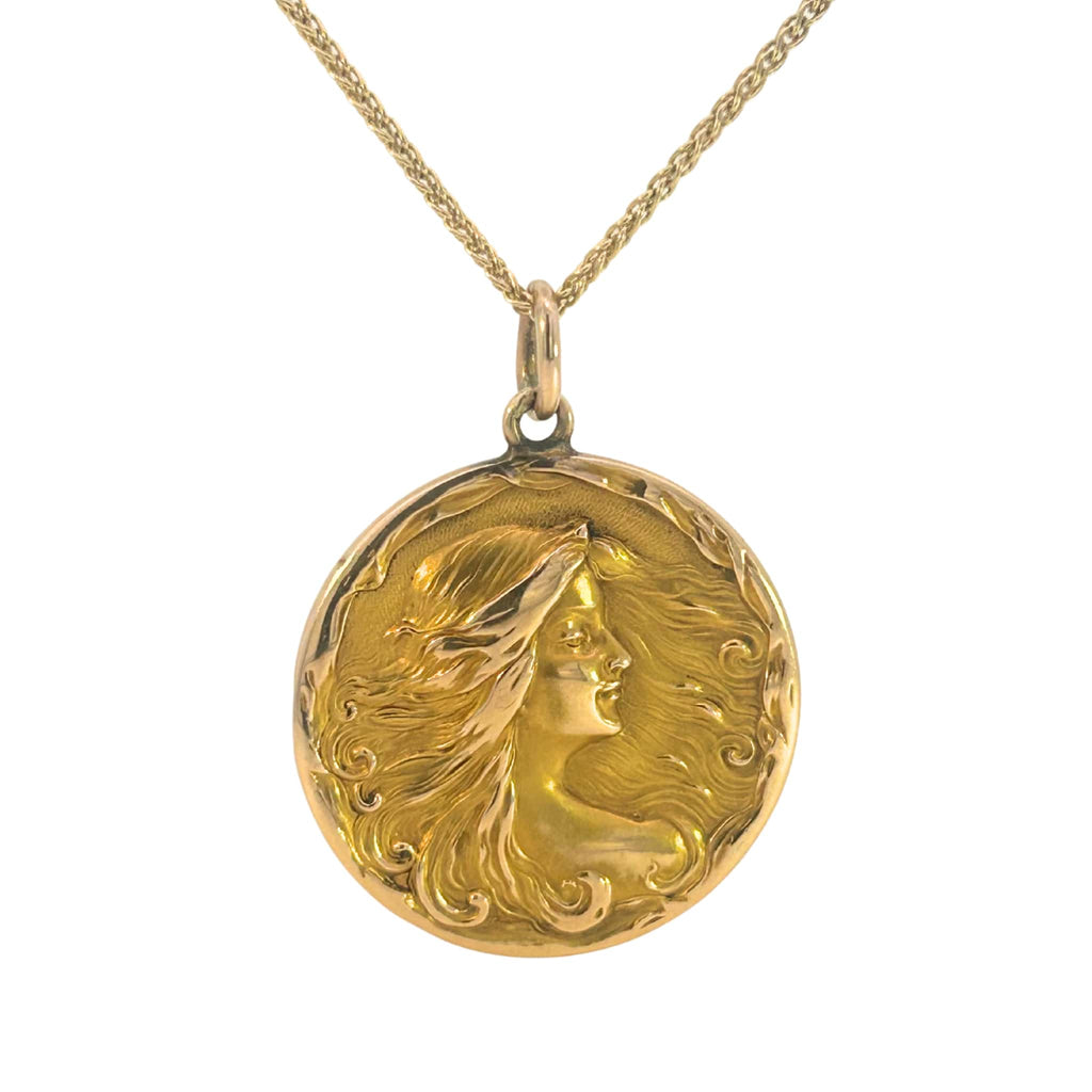 Antique Art Nouveau gold locket with raised profile of a woman, engraved monogram on reverse, and period photograph inside.
