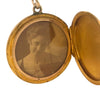 Antique Art Nouveau gold locket with raised profile of a woman, engraved monogram on reverse, and period photograph inside.