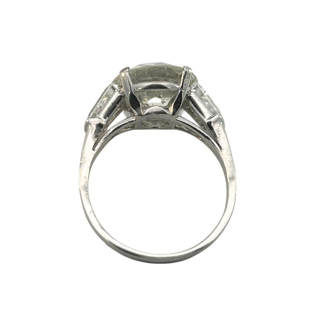 Vintage three-stone platinum ring featuring an European–cut diamond with tapered bullet side stones