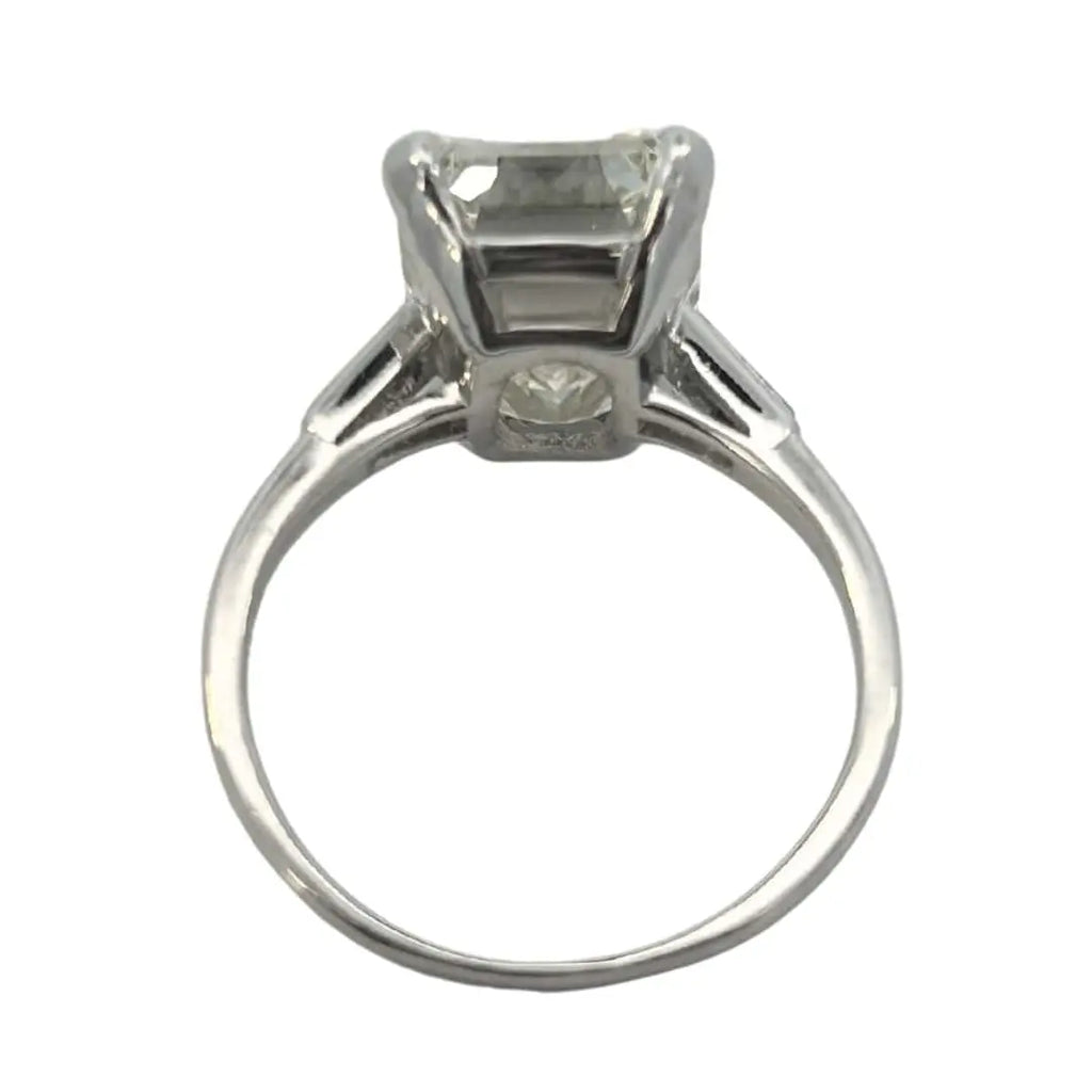 Platinum vintage emerald cut diamond engagement ring featuring a 6.02ct M/VS1 GIA-certified center stone with tapered baguette side diamonds.