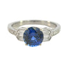 Front view of a platinum ring with round blue sapphire and tapered baguette diamond shoulders.