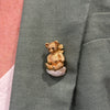 On mod view of William Ruser teddy bear brooch in 14k yellow gold with sapphire eyes seated on an American freshwater pearl.l