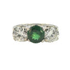 Three-stone ring with 1.63ct green tsavorite flanked by two round diamonds in an engraved white-metal mount.