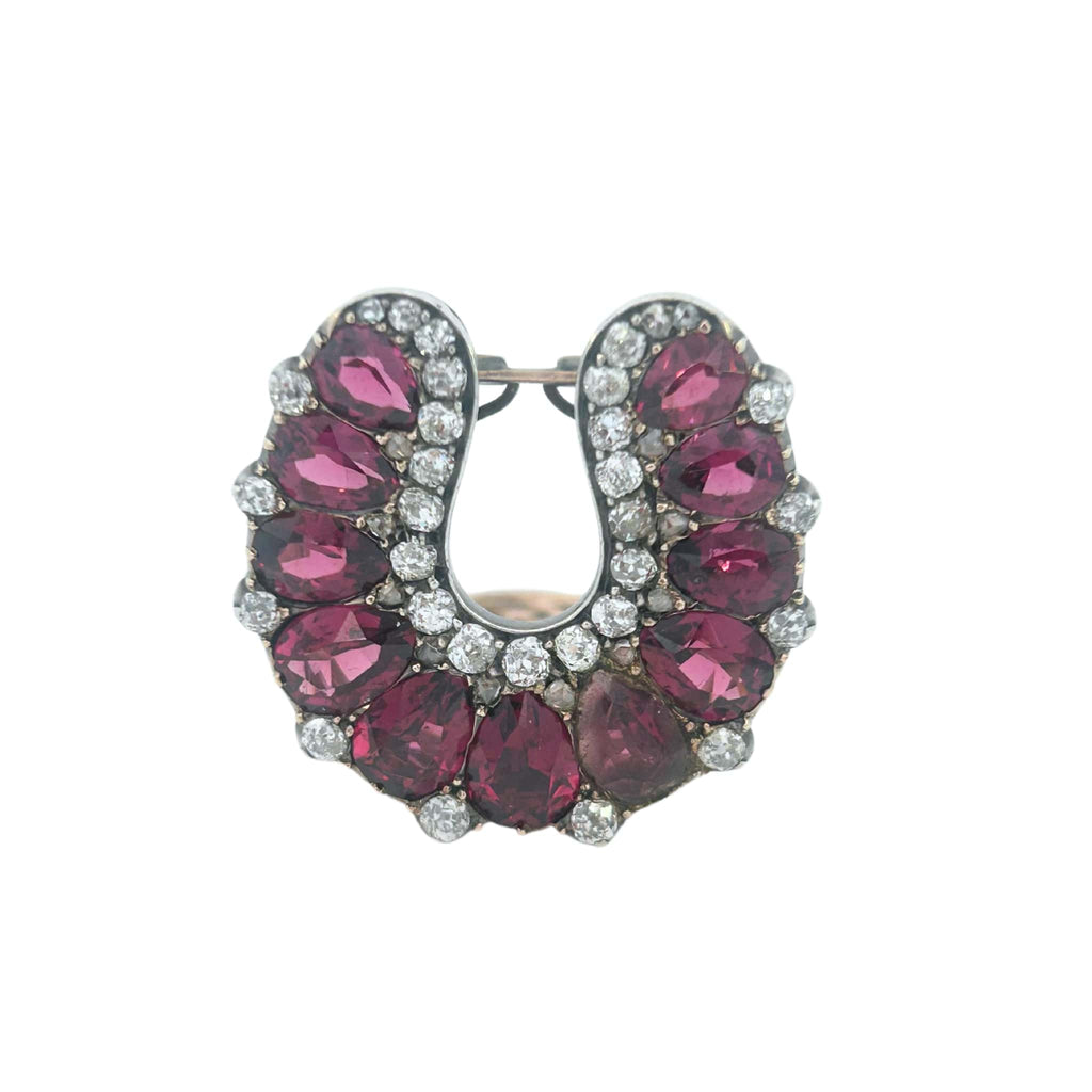 Front view of a Victorian horseshoe clip featuring rubies and antique diamonds in silver with a 10k gold back.
