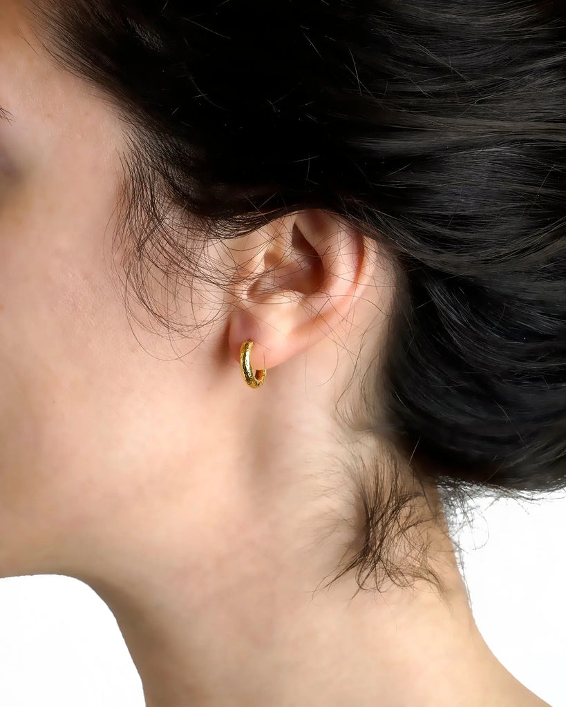 Baby hammered 19k yellow gold hoop earring shown worn on ear